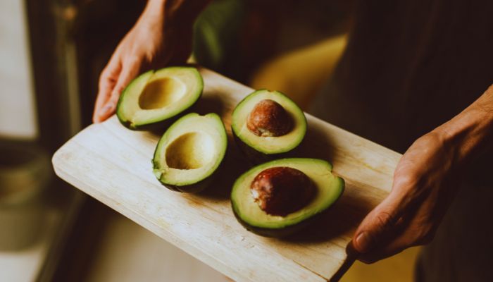 man holding avocado on tray